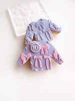 Decorative cookies shaped like dresses with bows on a white background