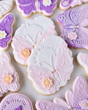 Decorative butterfly cookies with intricate designs on a white surface
