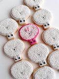 Decorative cookies shaped like sheep with white faces and black legs on a white background