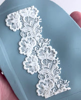 White lace trim held over a blue surface
