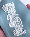 White lace trim held over a blue surface