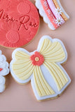 Decorative cookies with a yellow bow and red flower on a pink background