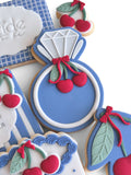Decorative cookies shaped like a diamond ring with cherries on a white surface.